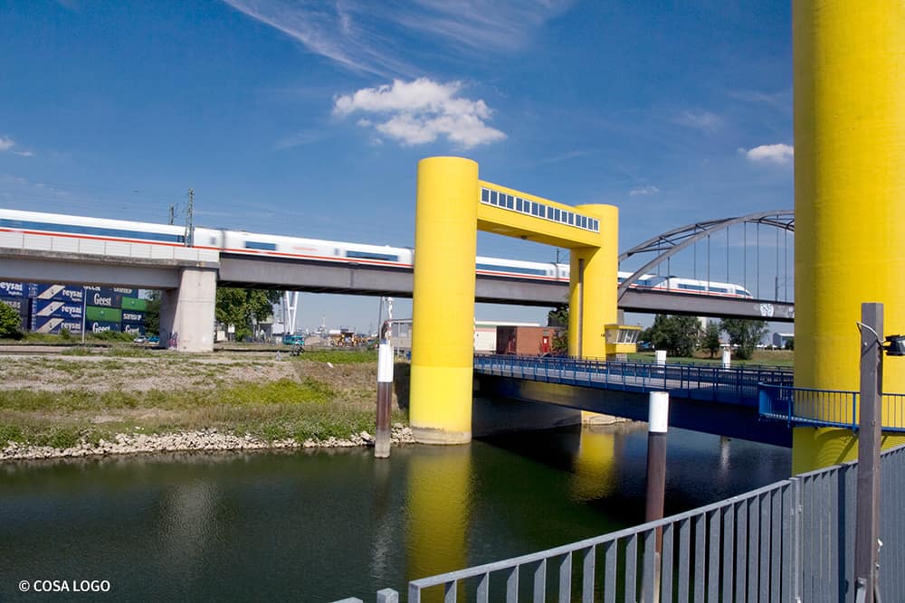 Seitenansicht der Neckarvorlandbrücke mit vorbeifahrendem Zug im Hintergrund.