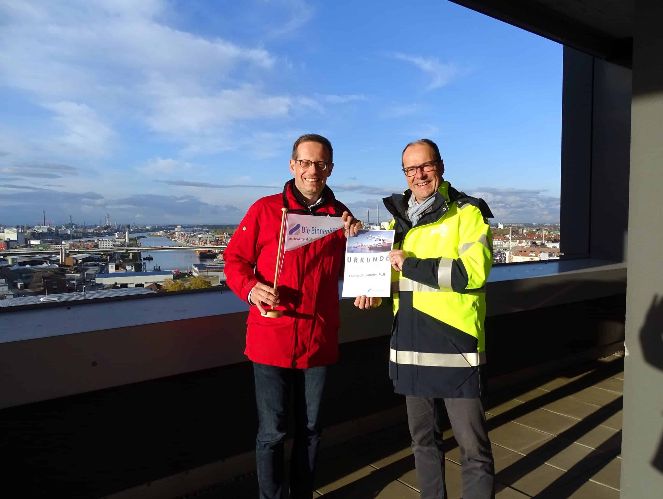 Herr Stockmeier und Herr Köhn (Hafendirektor Mannheim) stehen in der Sonne auf einer Brücke.